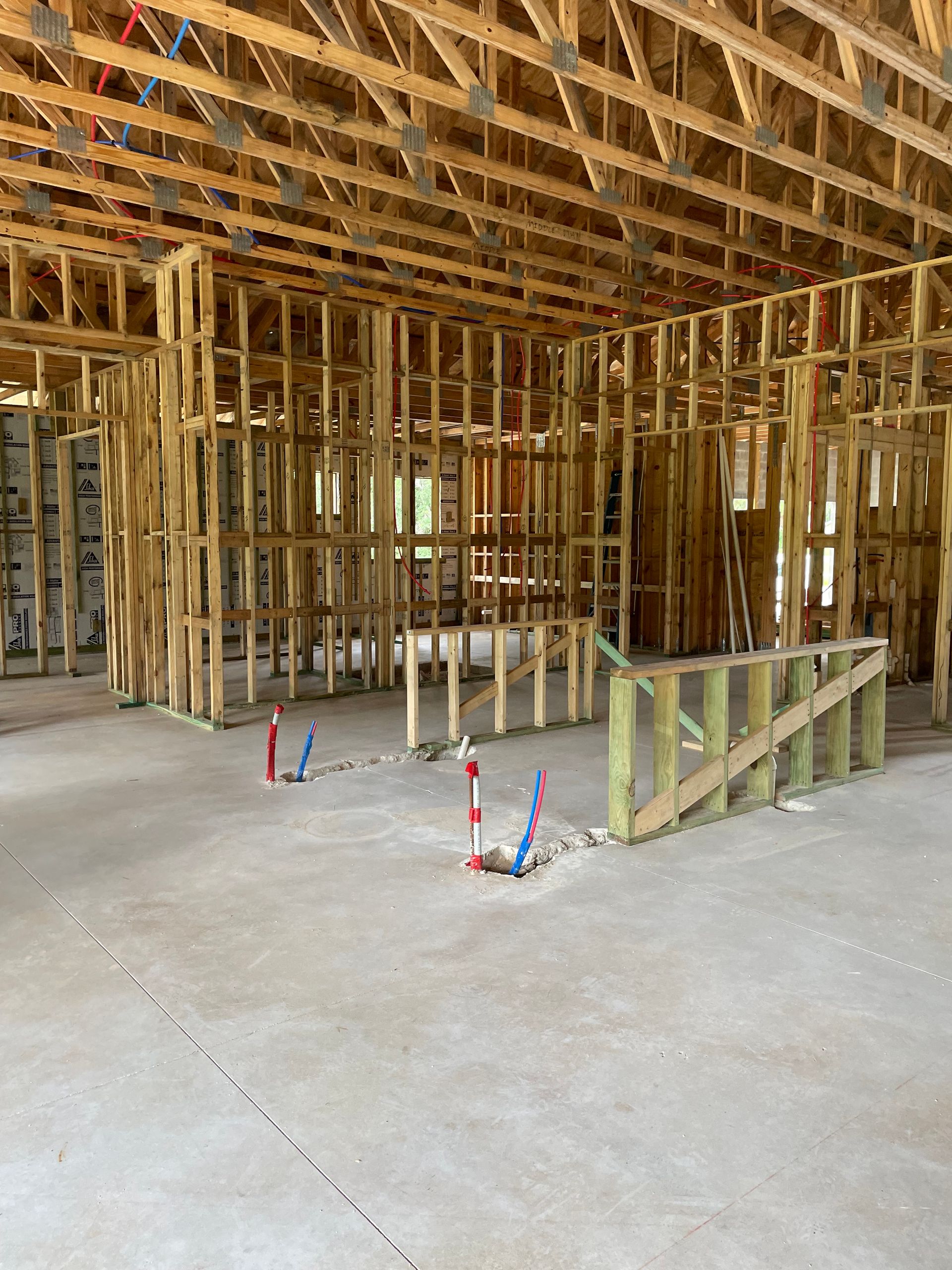 Unfinished house interior with exposed wooden framing, concrete floor, and temporary support braces.