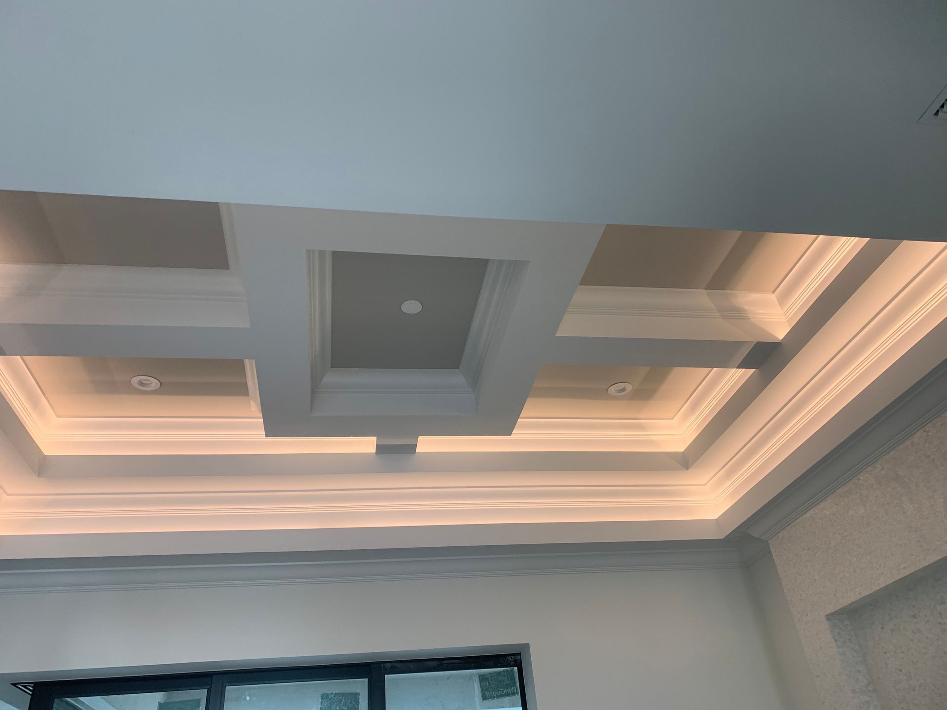 Modern ceiling with layered recessed panels and warm cove lighting in a room