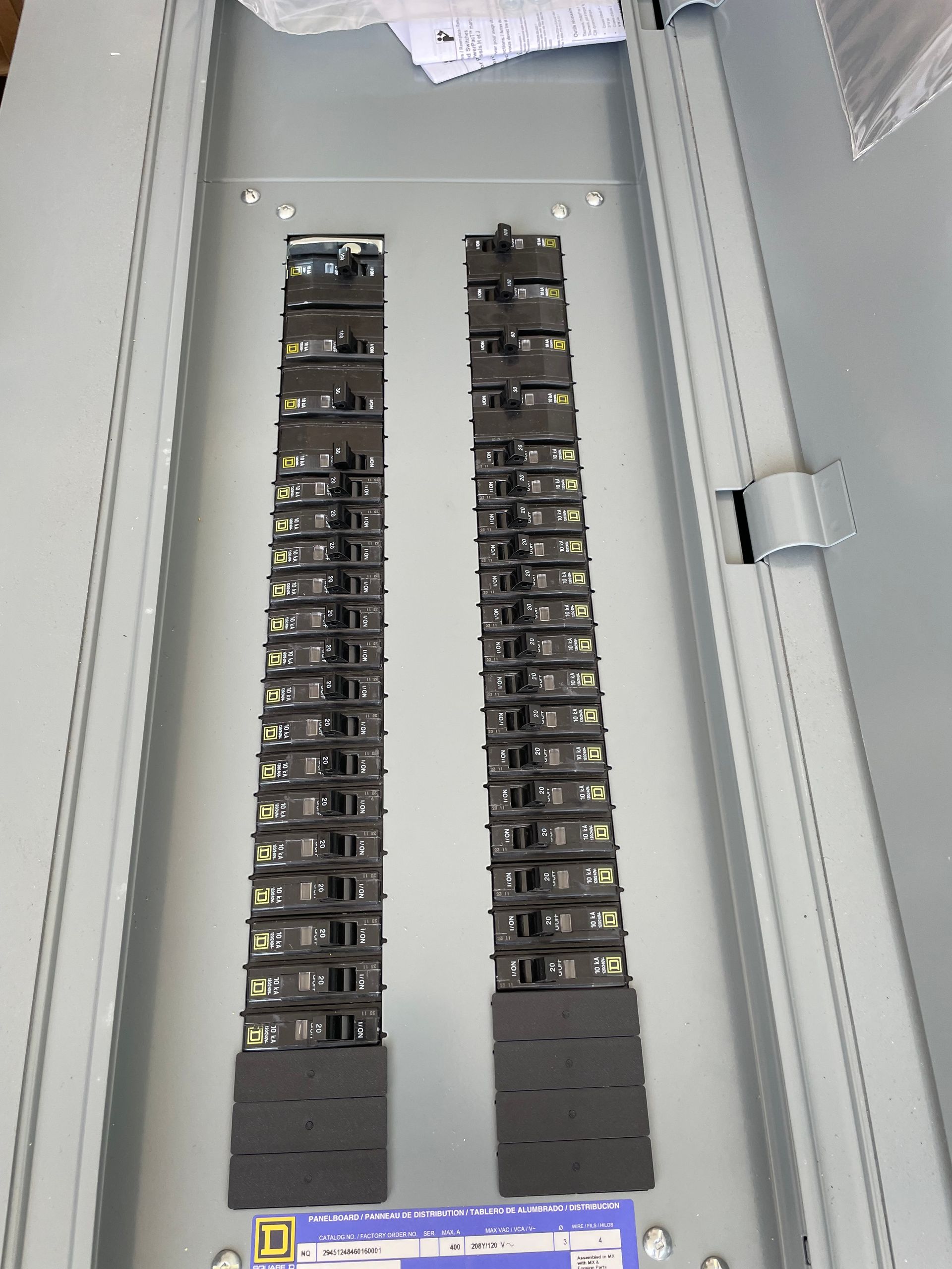 Open electrical panel with two rows of breakers inside a gray metal cabinet.