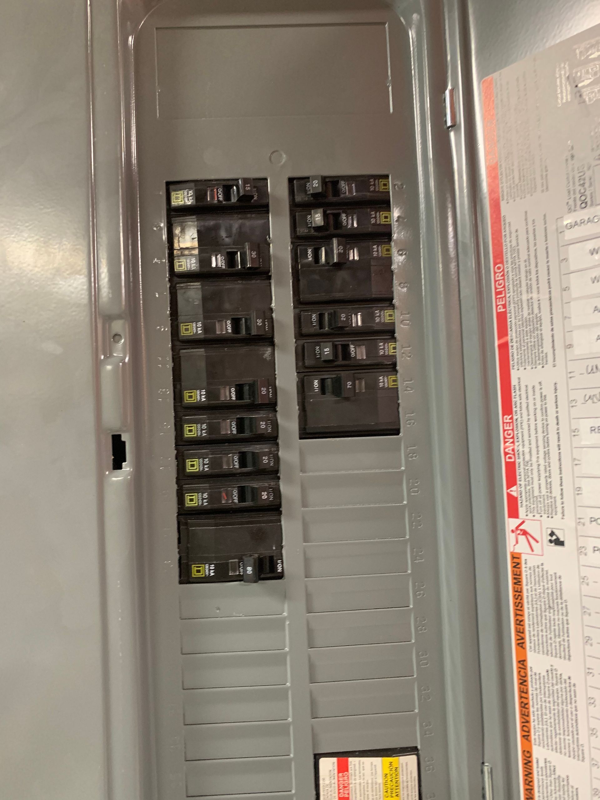 Open electrical breaker panel with rows of switches and a circuit directory label.