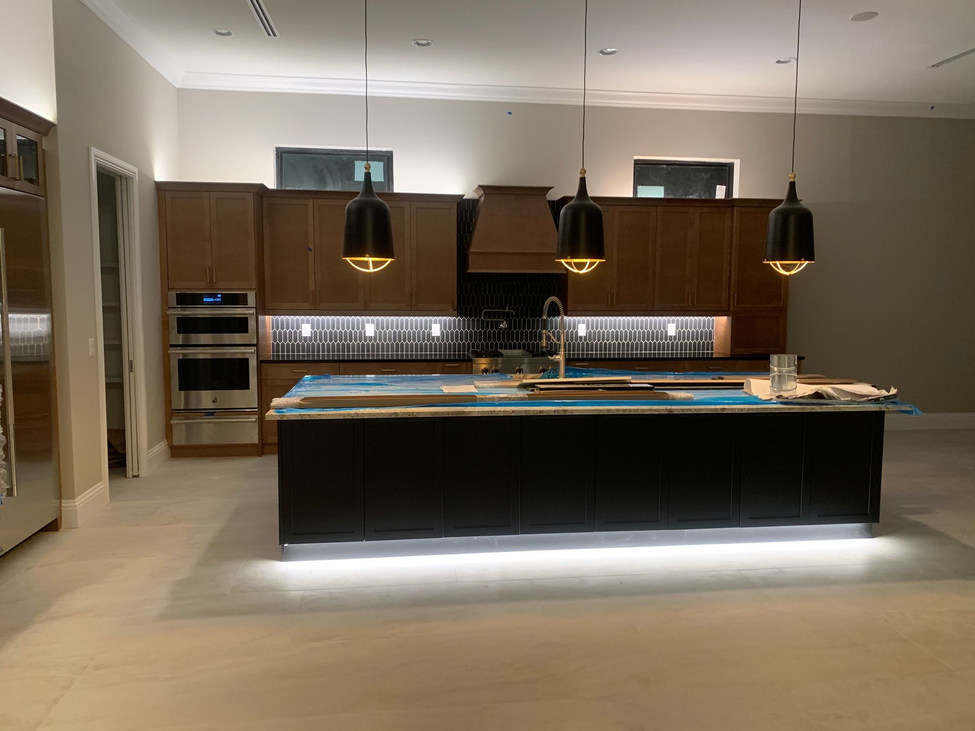 Modern kitchen with a large island, dark wood cabinets, pendant lights, and under-cabinet lighting.