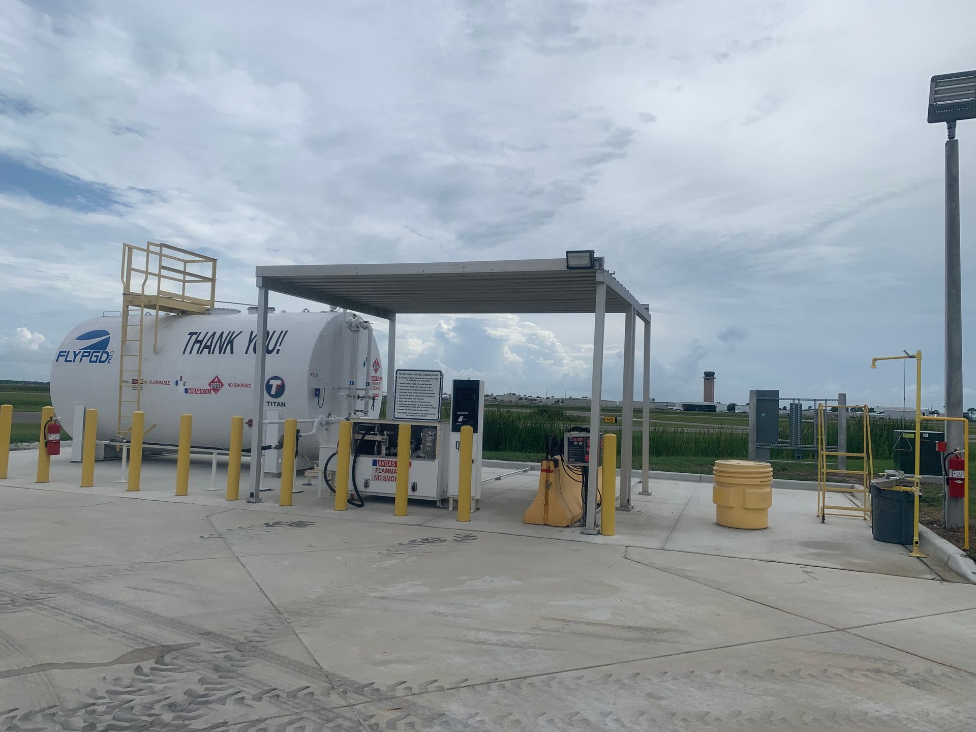 Industrial fuel tanker at a gated gas station under a cloudy sky