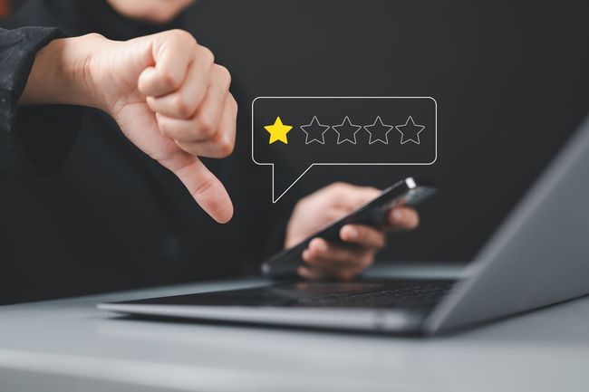 Person gives thumbs-down, looking at phone and laptop; one-star review graphic appears.