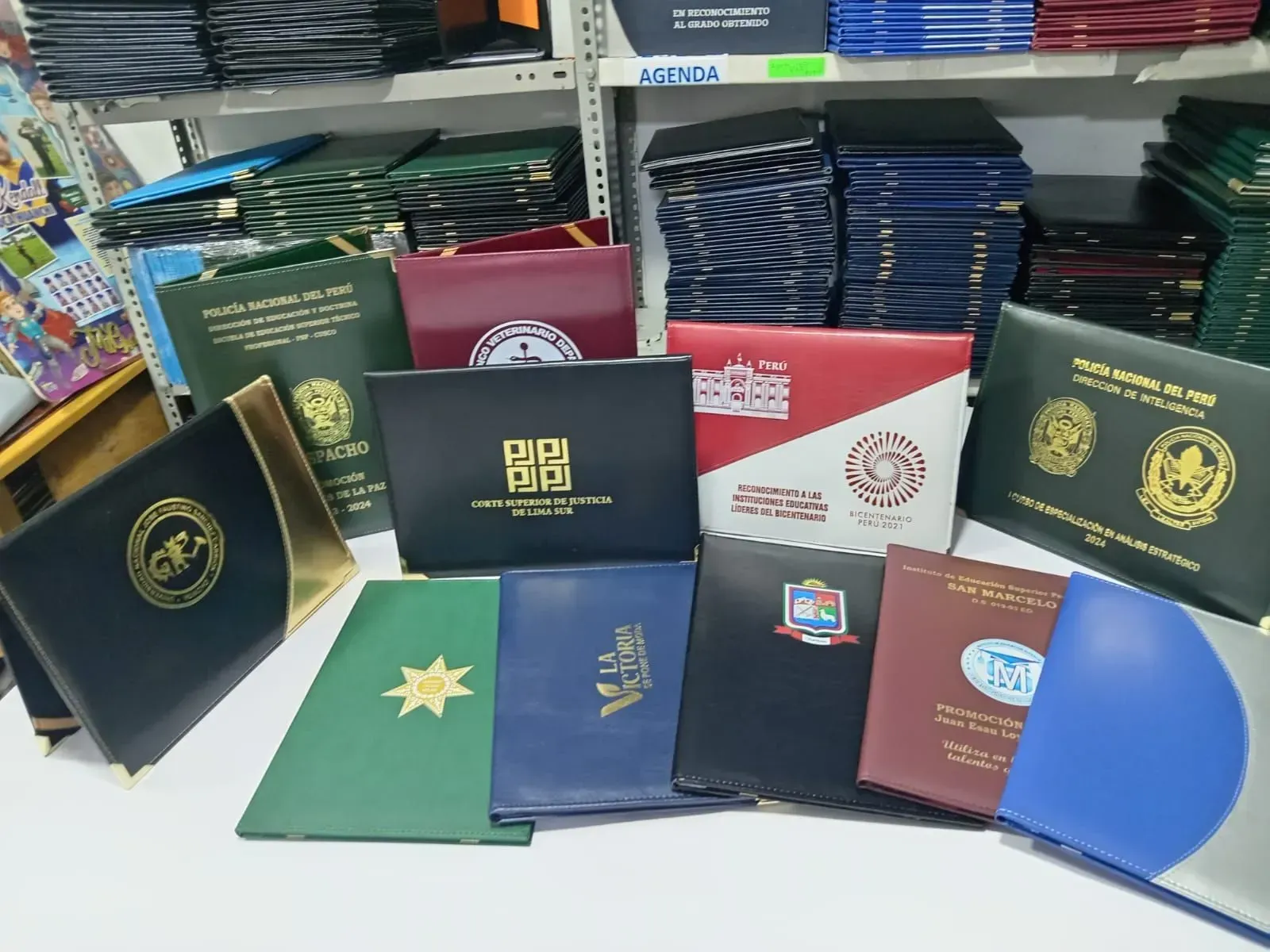 Varios pasaportes y cuadernos expuestos en el mostrador de una tienda, con tapas coloridas y emblemas dorados.