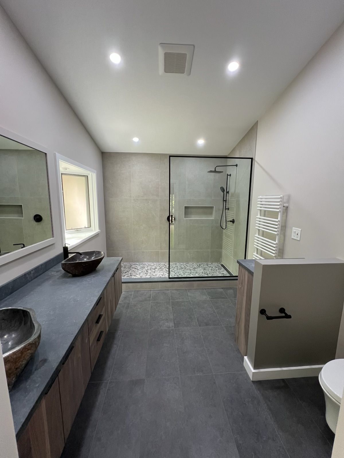 A bathroom with a walk in shower , sink and toilet.
