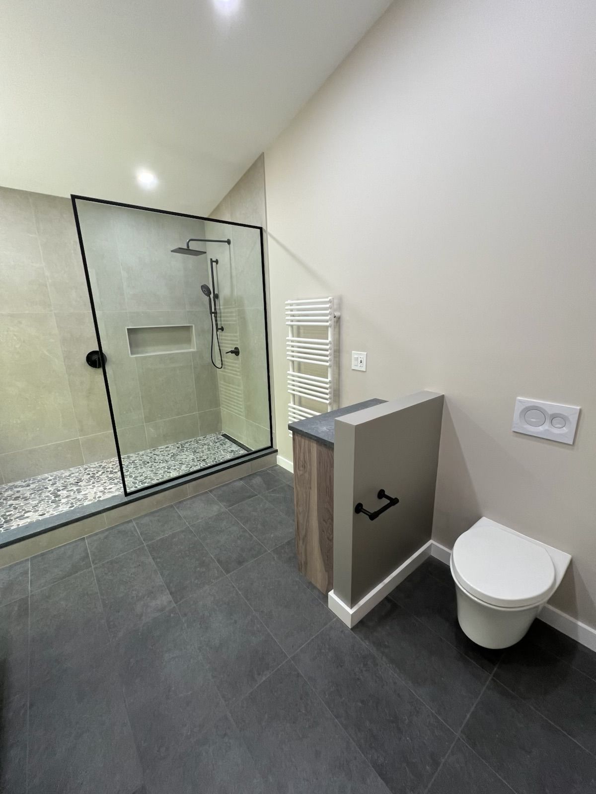 A bathroom with a toilet , shower , and towel rack.