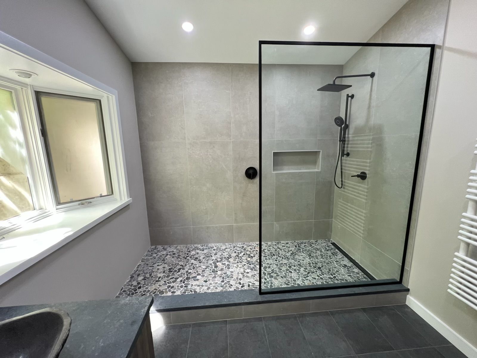 A bathroom with a walk in shower and a sink