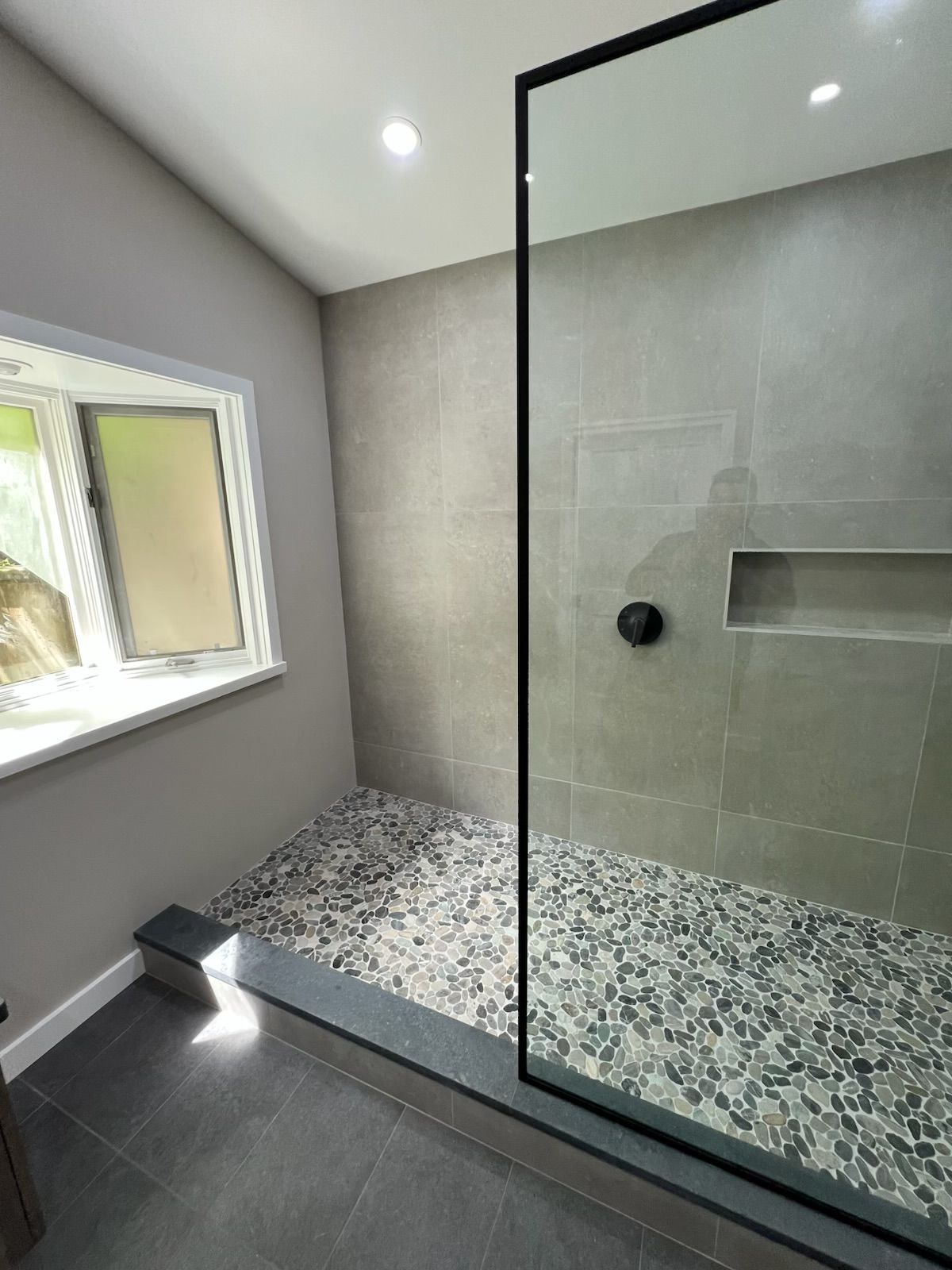 A bathroom with a walk in shower and a window.
