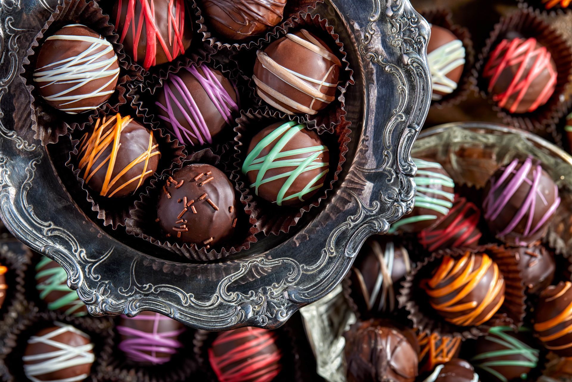 Tray of chocolate truffles, each with colorful drizzle on dark chocolate.
