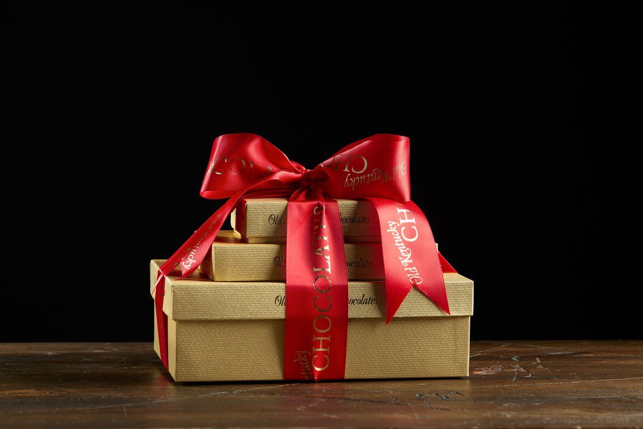 Gift boxes stacked and tied with a red ribbon on a wooden surface.