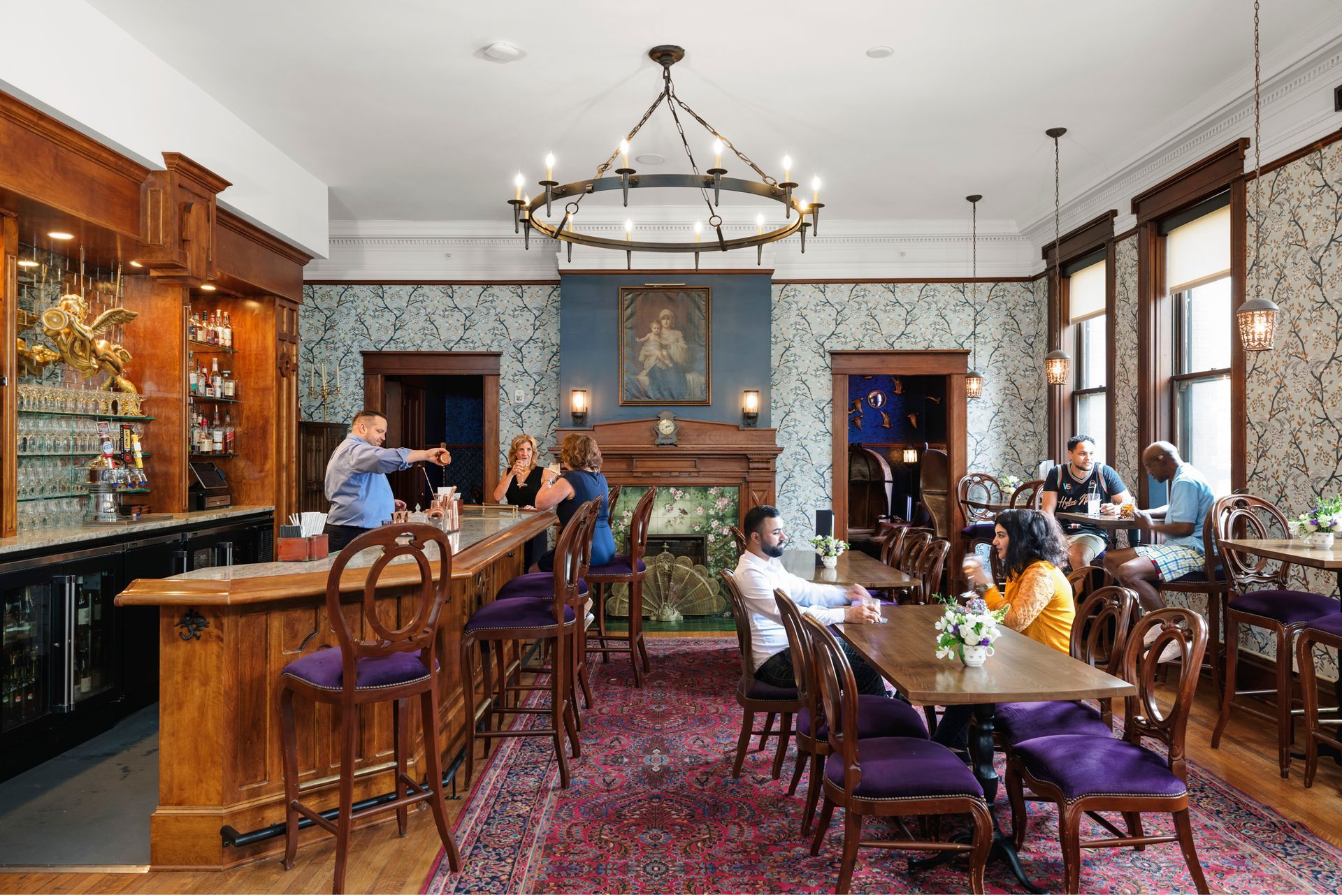 Elegant pub dining room with people seated at tables, wood bar, blue brick walls, and large windows