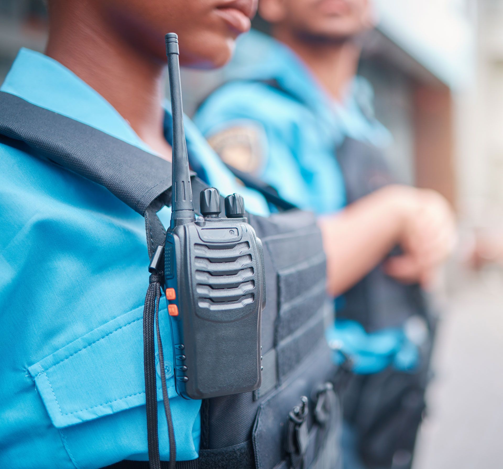 Close-up of police officers in blue uniforms wearing tactical vests and radios