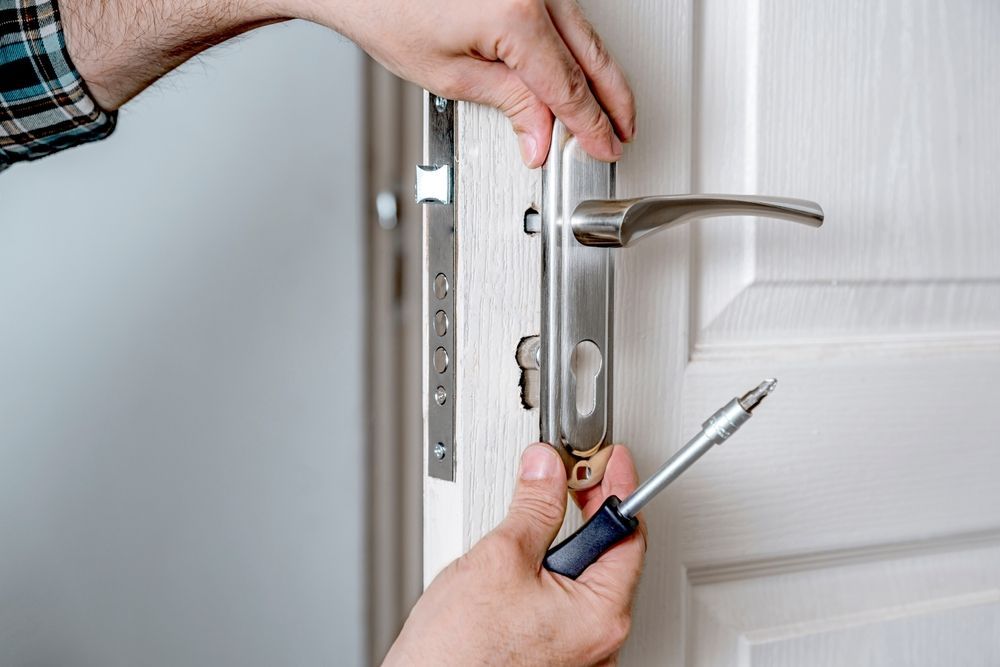 A man is fixing a door with a screwdriver.