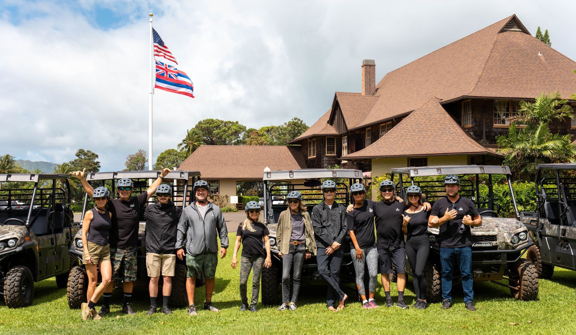 Group of people in tactical gear posing in front of a large lodge with an American flag.