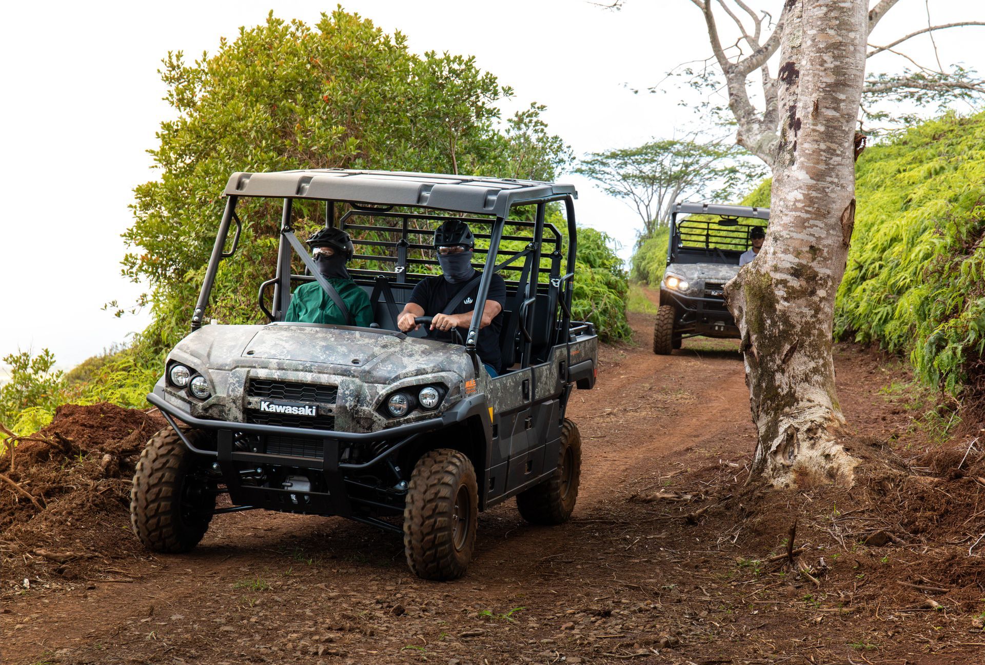 Off-road buggy driving on a muddy trail with another vehicle behind it