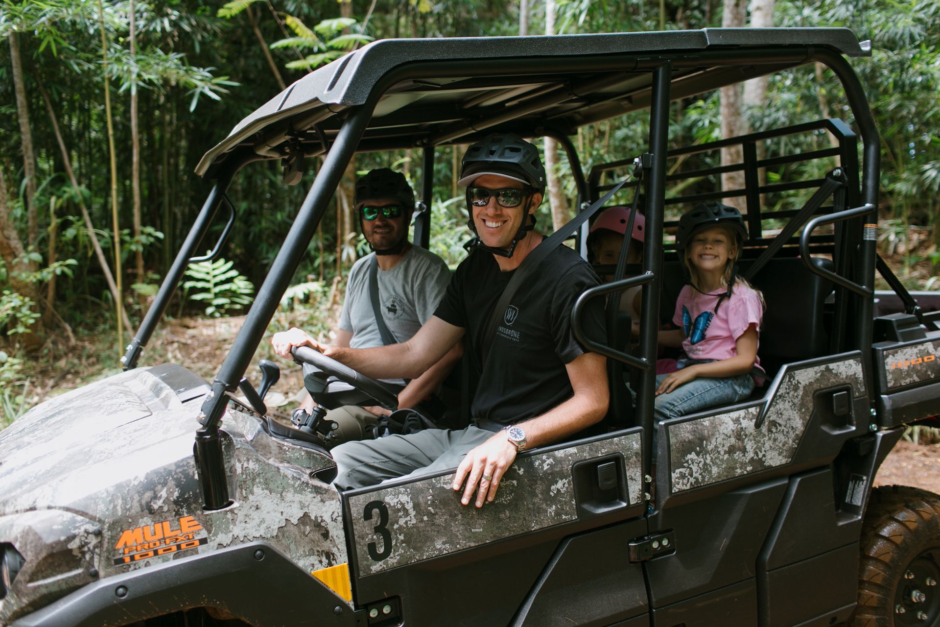 Off-road buggy with four passengers driving through a muddy forest trail
