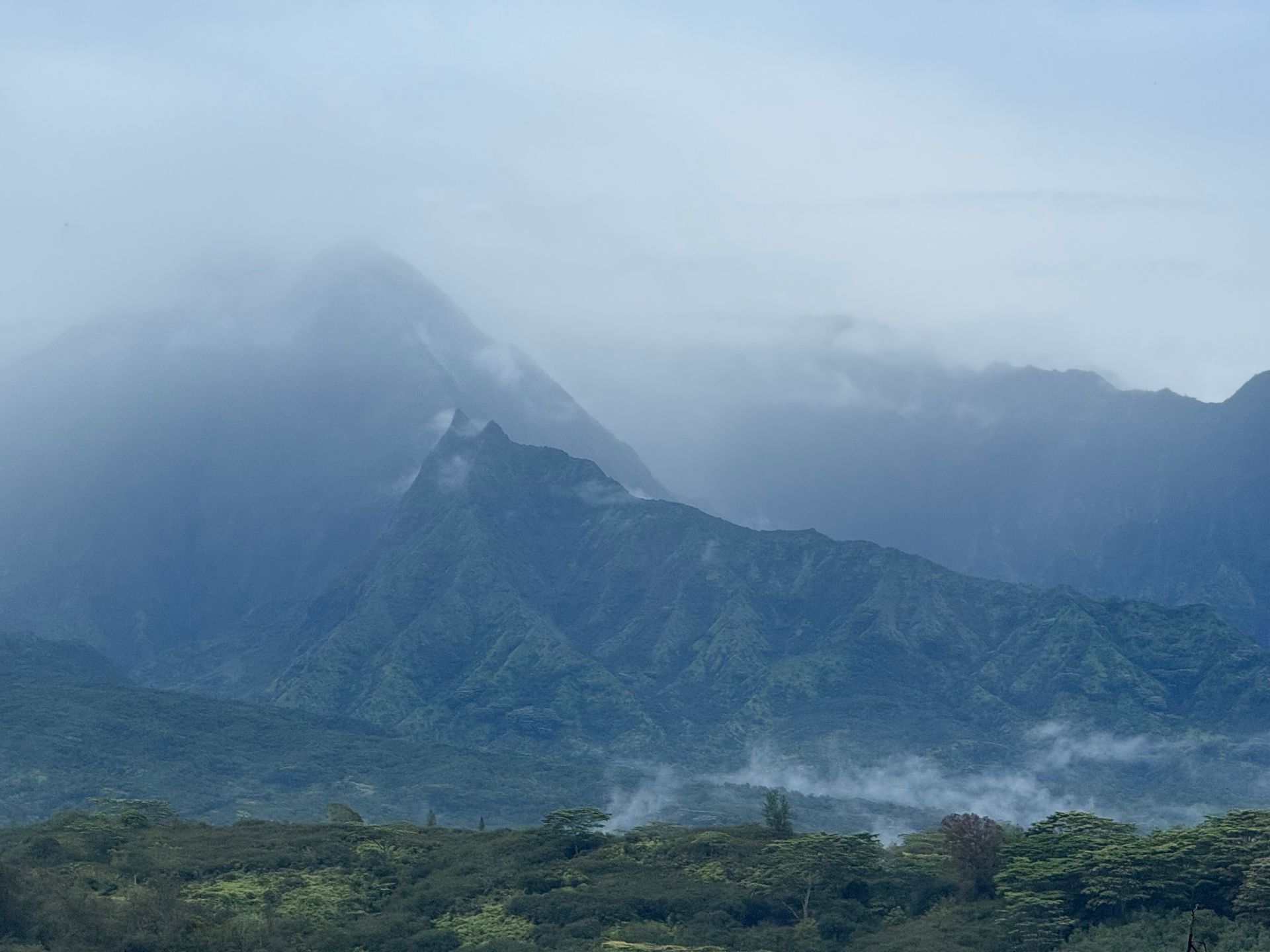 Foggy mountain landscape with green ridges and low clouds over the peaks