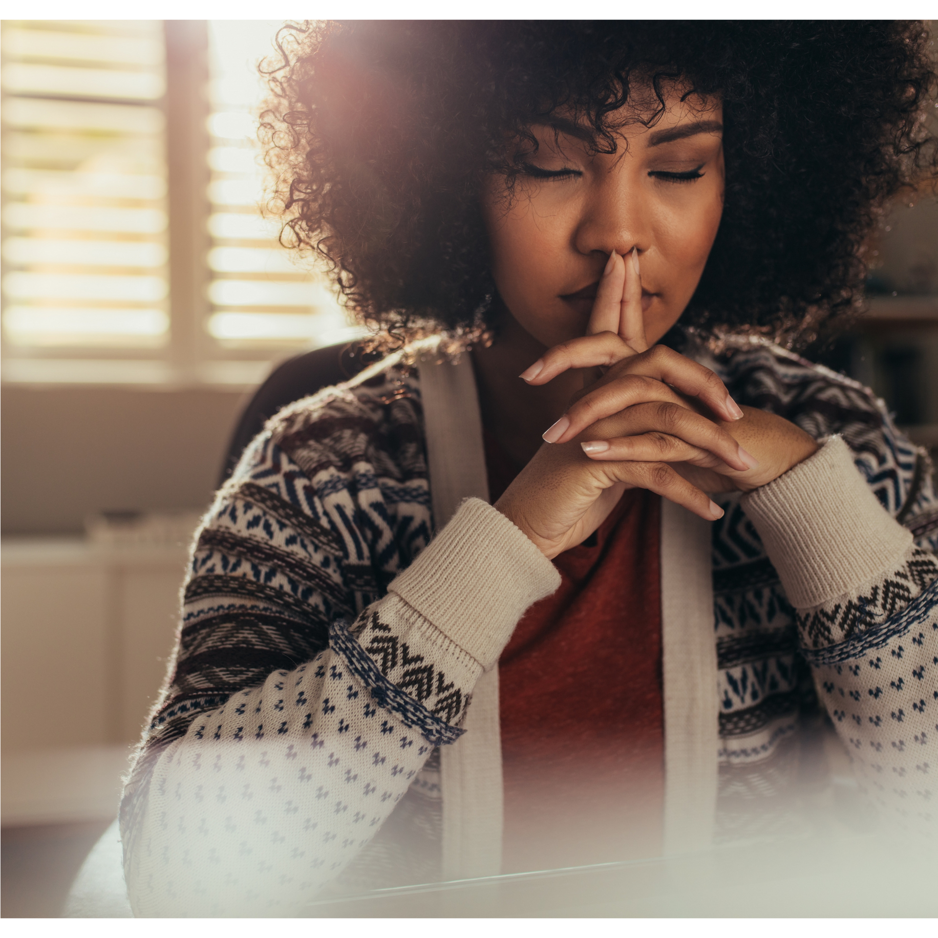 A woman in a sweater is covering her mouth with her hands