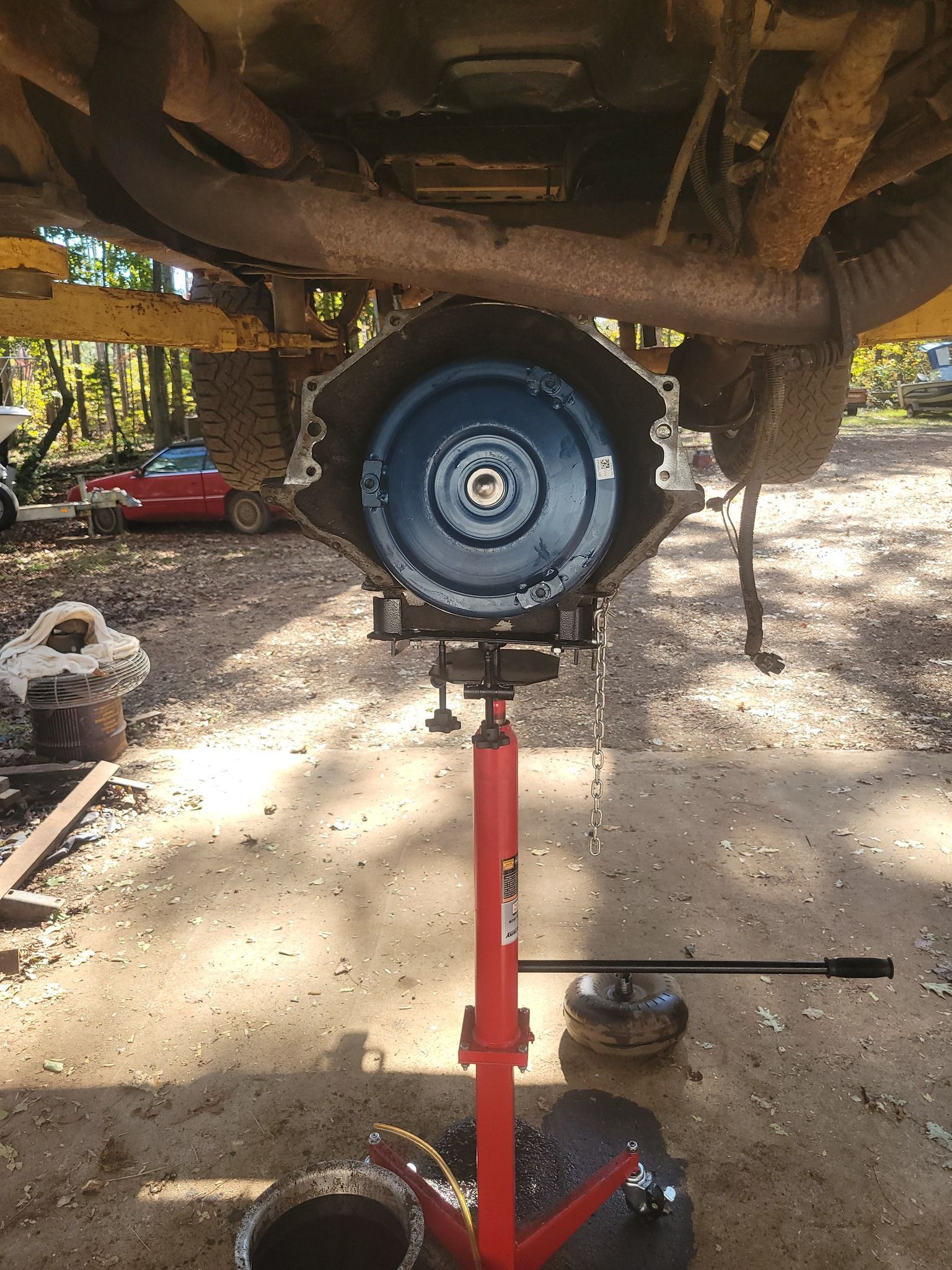 A clutch is sitting on a red stand under a car.