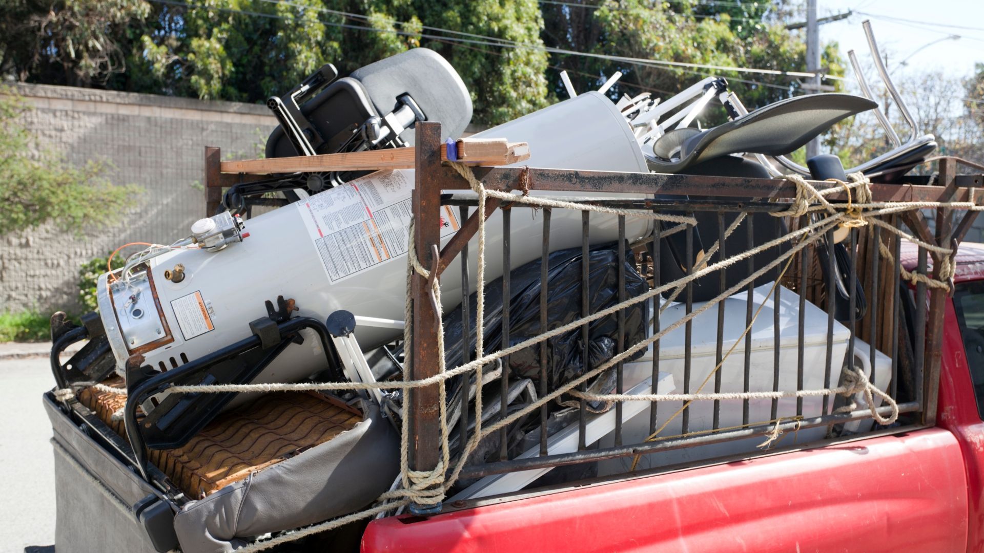 A red truck is loaded with a lot of junk in the back.