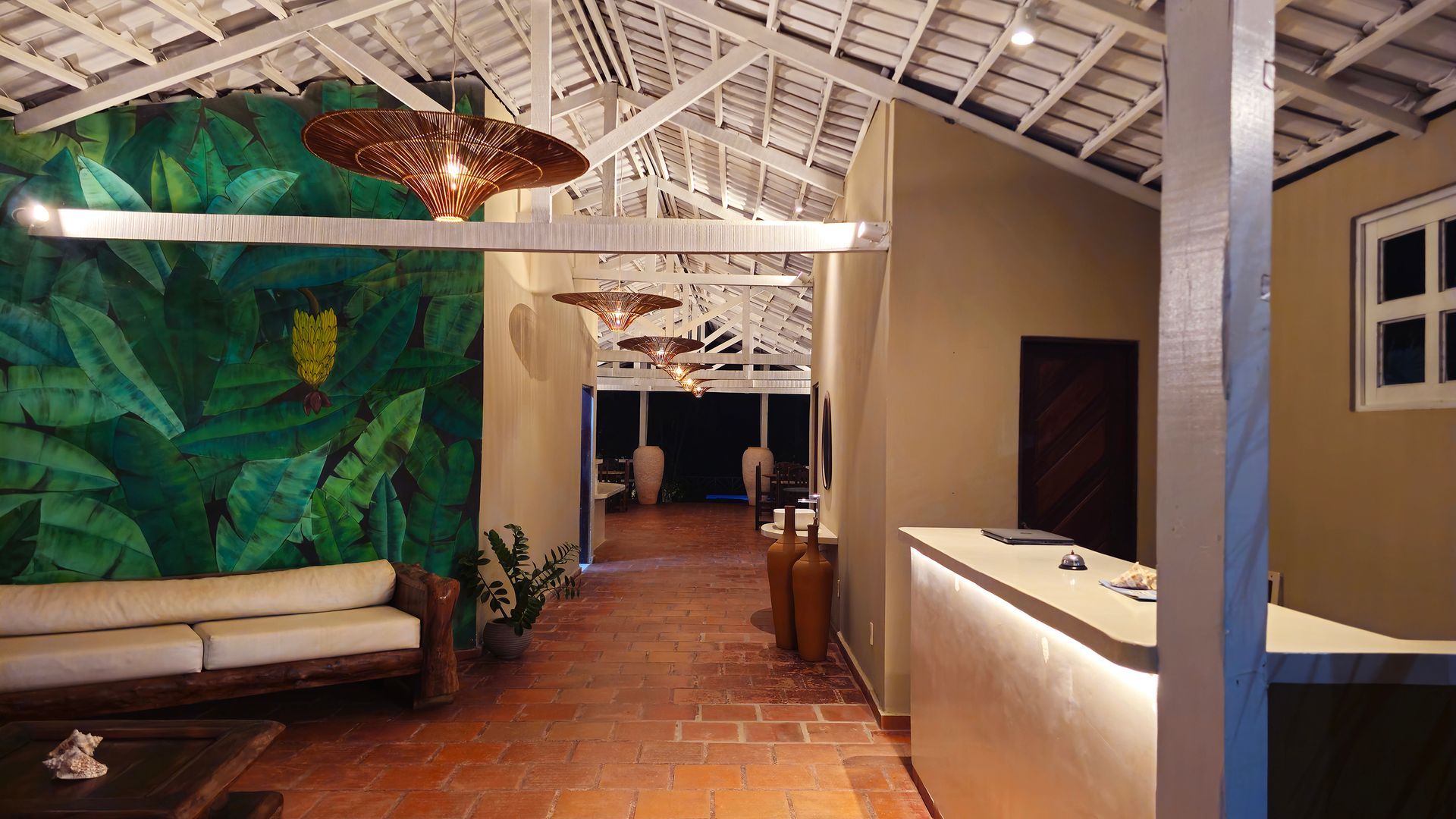 Lobby with white ceiling, tropical mural, wooden sofa, tiled floor, and reception desk.