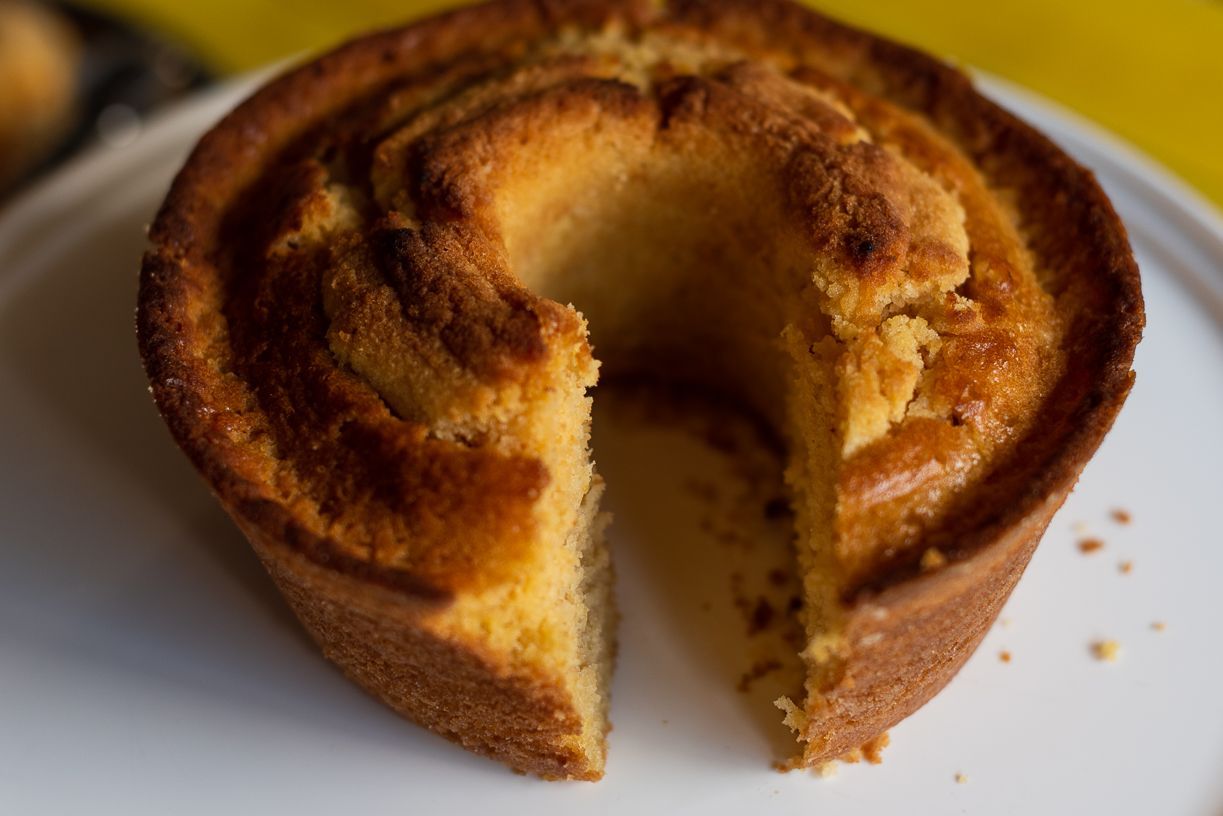 Yellow bundt cake on a white plate, slice removed, revealing interior.