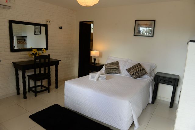 Bedroom with white walls, bed, desk with mirror, and small side table.