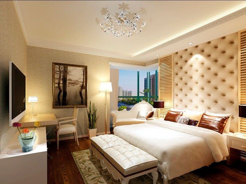 Elegant bedroom with a large bed, tufted headboard, desk, and a window overlooking a cityscape.