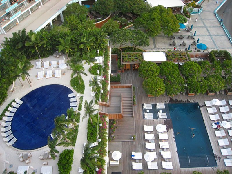 Aerial view of resort with pools, lounge chairs, and lush greenery.