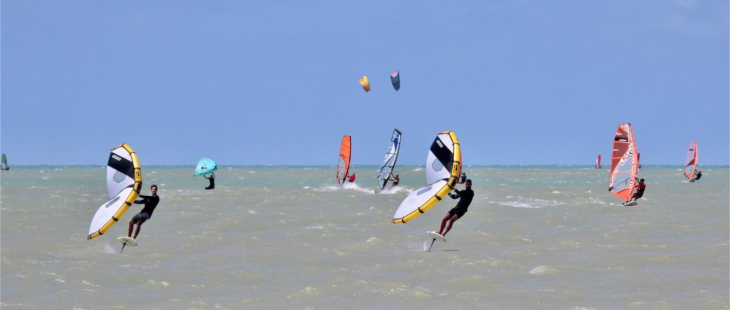 Windsurfers on the water under a clear blue sky.