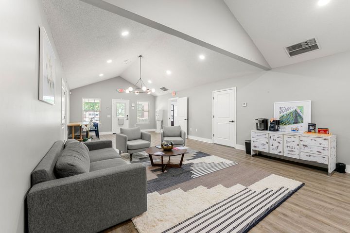 Bright open living room with gray sofa, patterned rugs, white walls, and ceiling lights