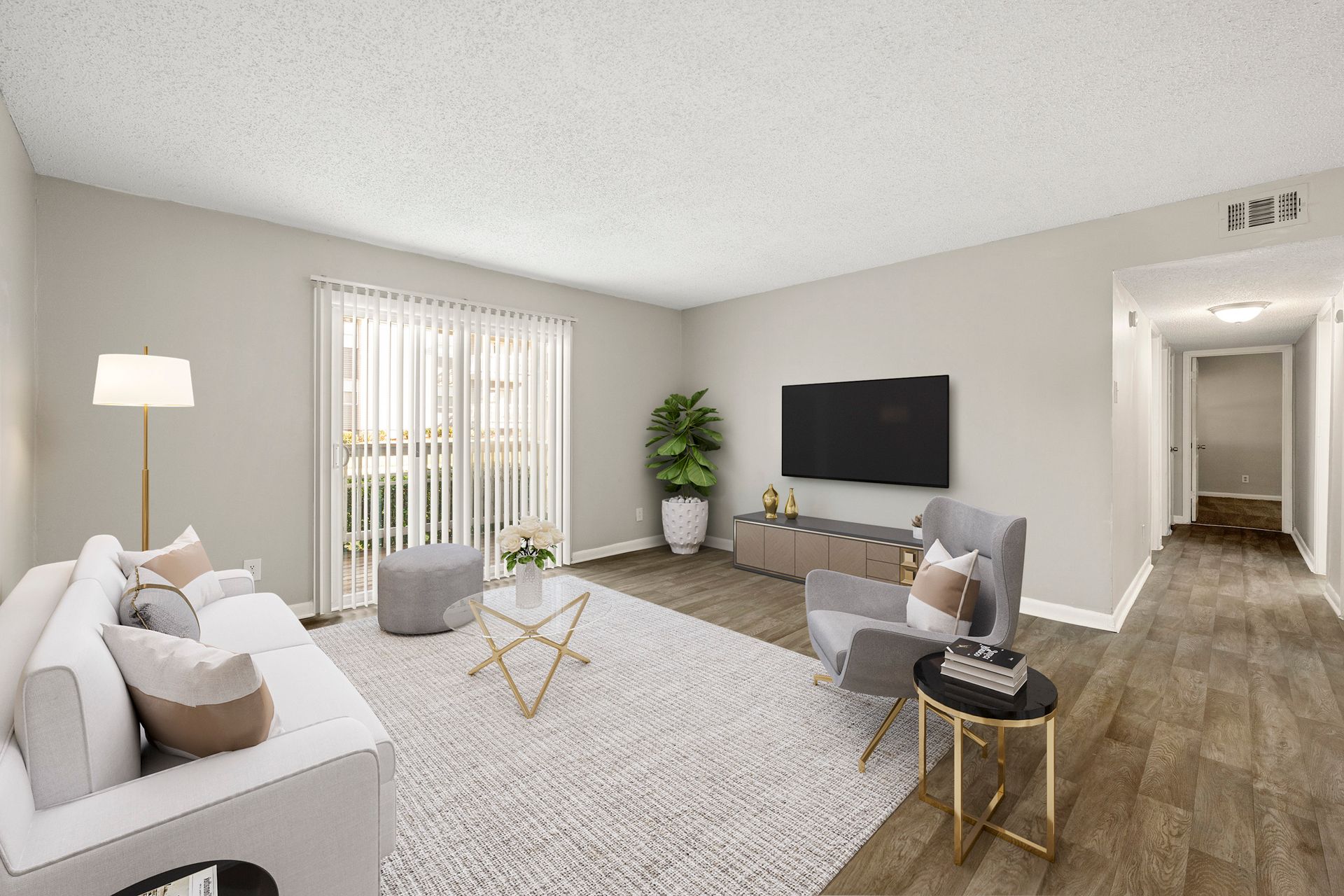 Modern living room with white sofa, wall-mounted TV, gray chair, plant, and sliding glass doors