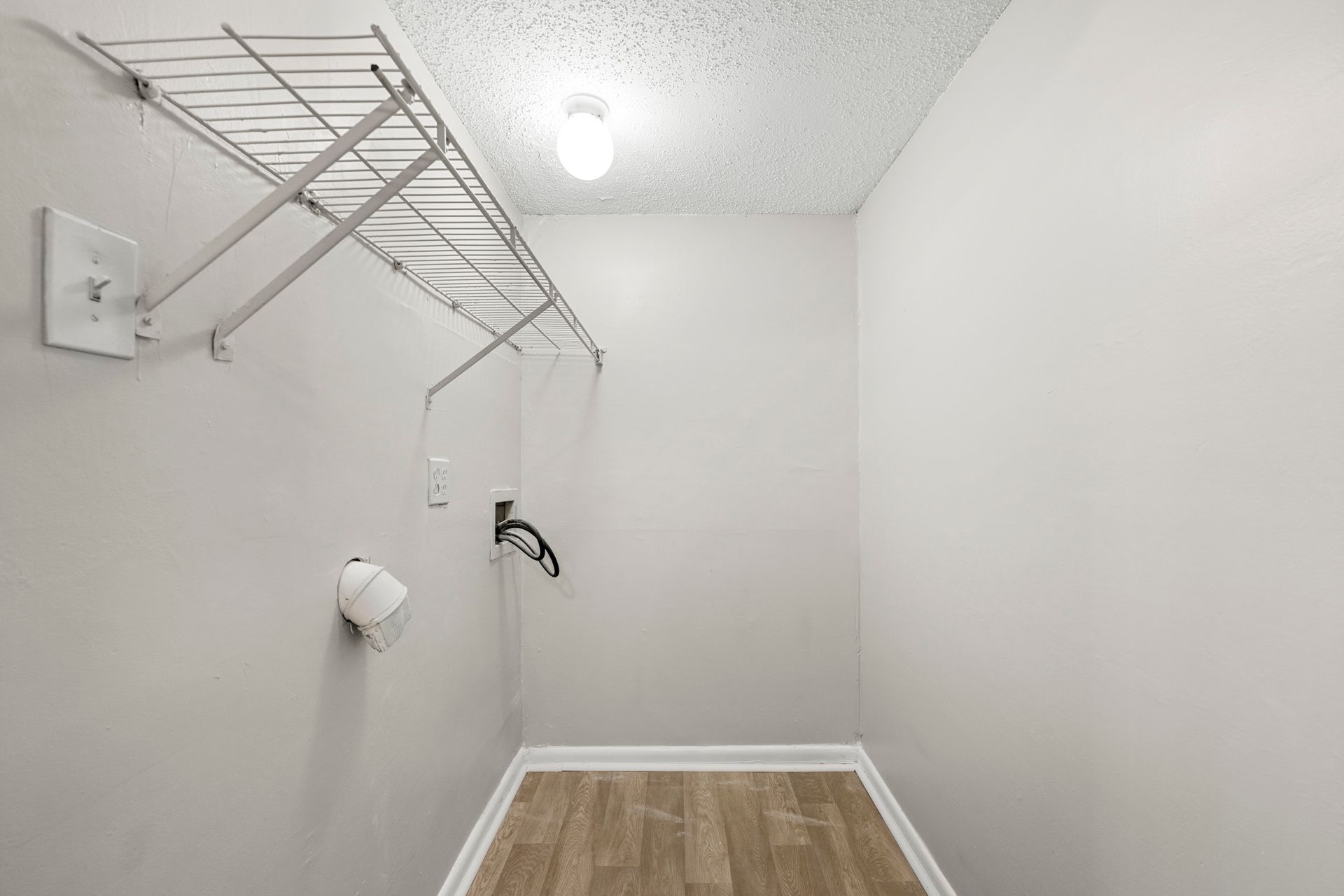 Empty walk-in closet with wire shelving, white walls, and wood-look flooring.
