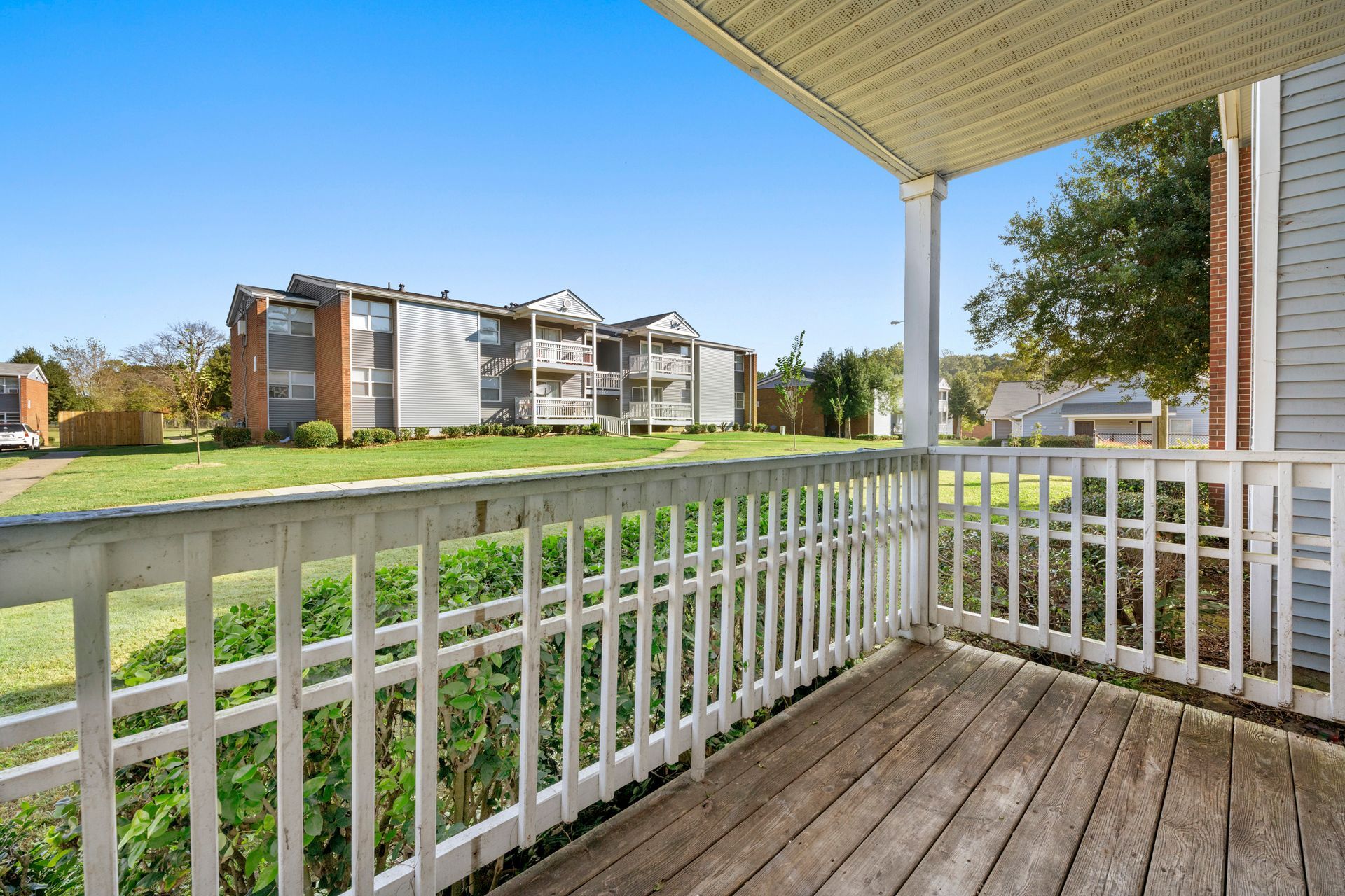 Covered porch overlooking grassy courtyard and apartment buildings