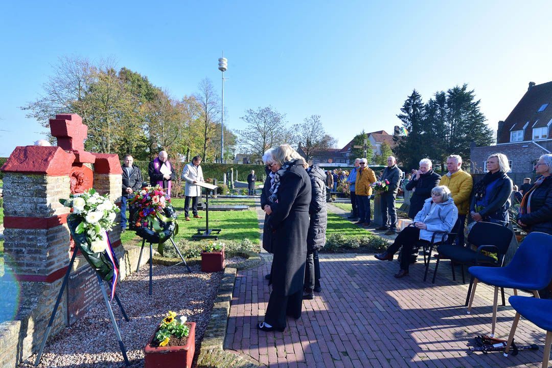 Mensen verzamelen zich bij een gedenkmonument voor een ceremonie in de openlucht op een zonnige dag.