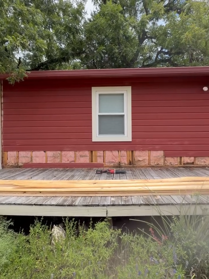 Red house exterior with white-framed window and a raised wooden deck in front