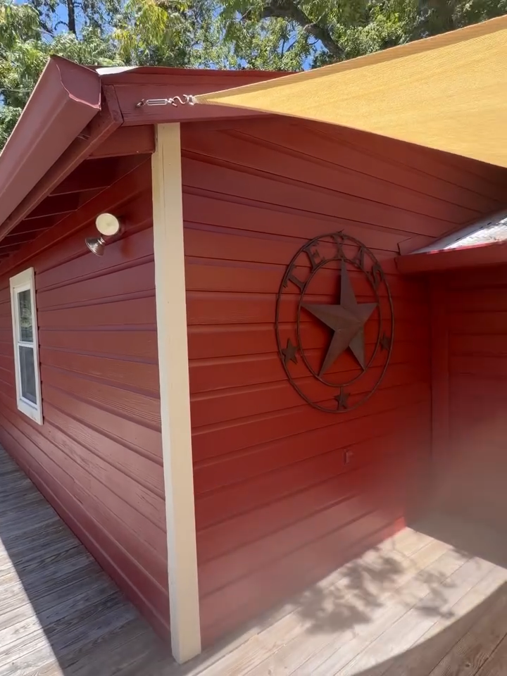Red house exterior with cream trim, star wall decor, and a small window under a sloped roof.