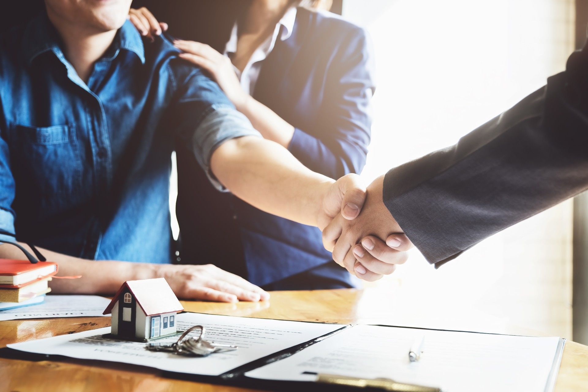 A man and a woman are shaking hands with a real estate agent.