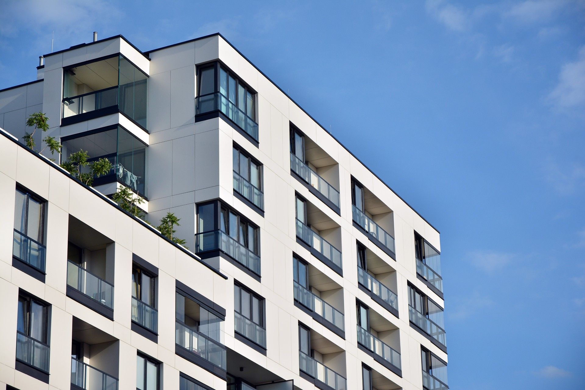 A large apartment building with a lot of windows and balconies against a blue sky.