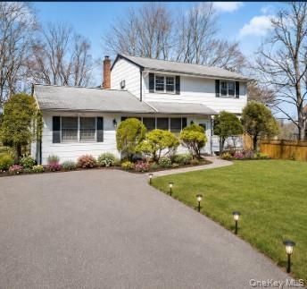 White two-story suburban house with gray roof, landscaped front yard, and wide paved driveway