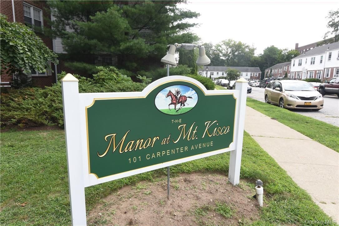 Green sign for Manor at Midlothian in front of townhomes and a street