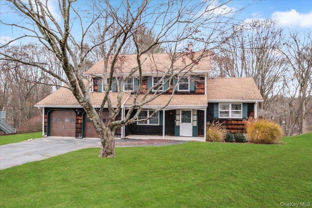 Two-story suburban house with attached garage, front lawn, and bare trees in early spring