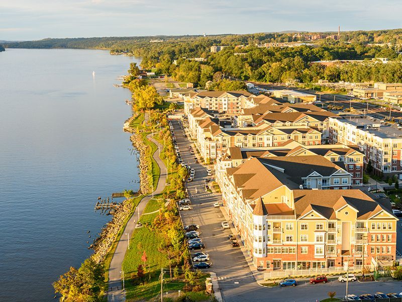 Aerial view of waterfront apartments and road beside a calm lake at sunset