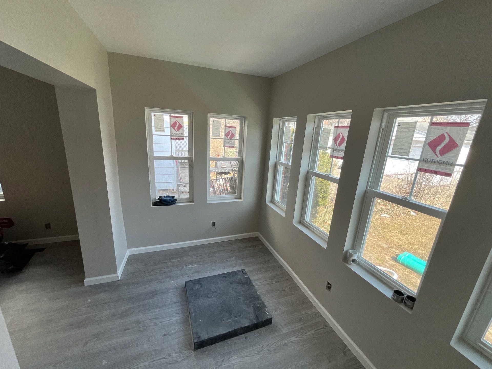 Empty bright room with gray walls, multiple windows, and carpet flooring.