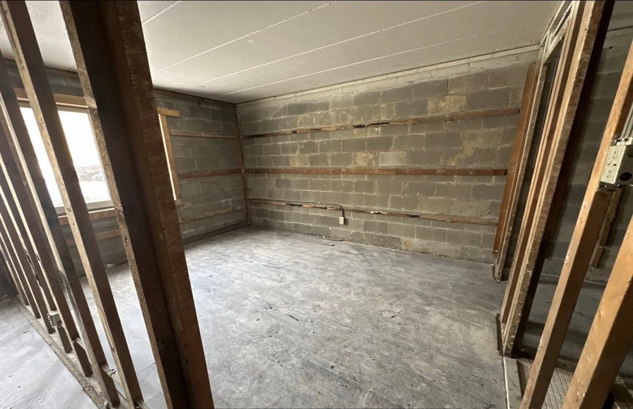 Unfinished room with exposed wooden framing, concrete floor, and unfinished walls and ceiling.