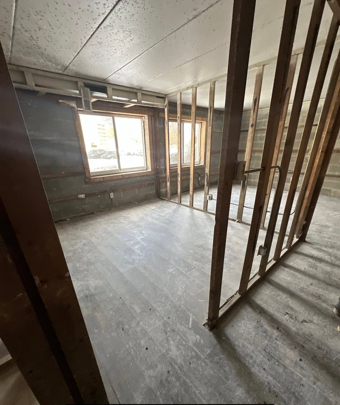 Unfinished room with exposed studs, concrete floor, and windows letting in daylight.
