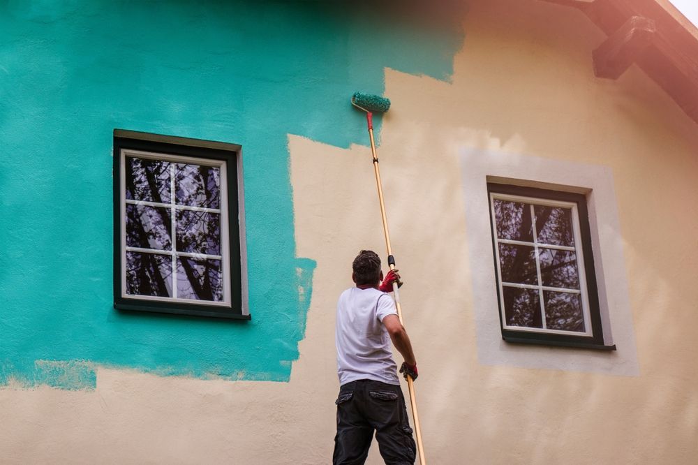 Person painting a wall turquoise and peach beside two windows