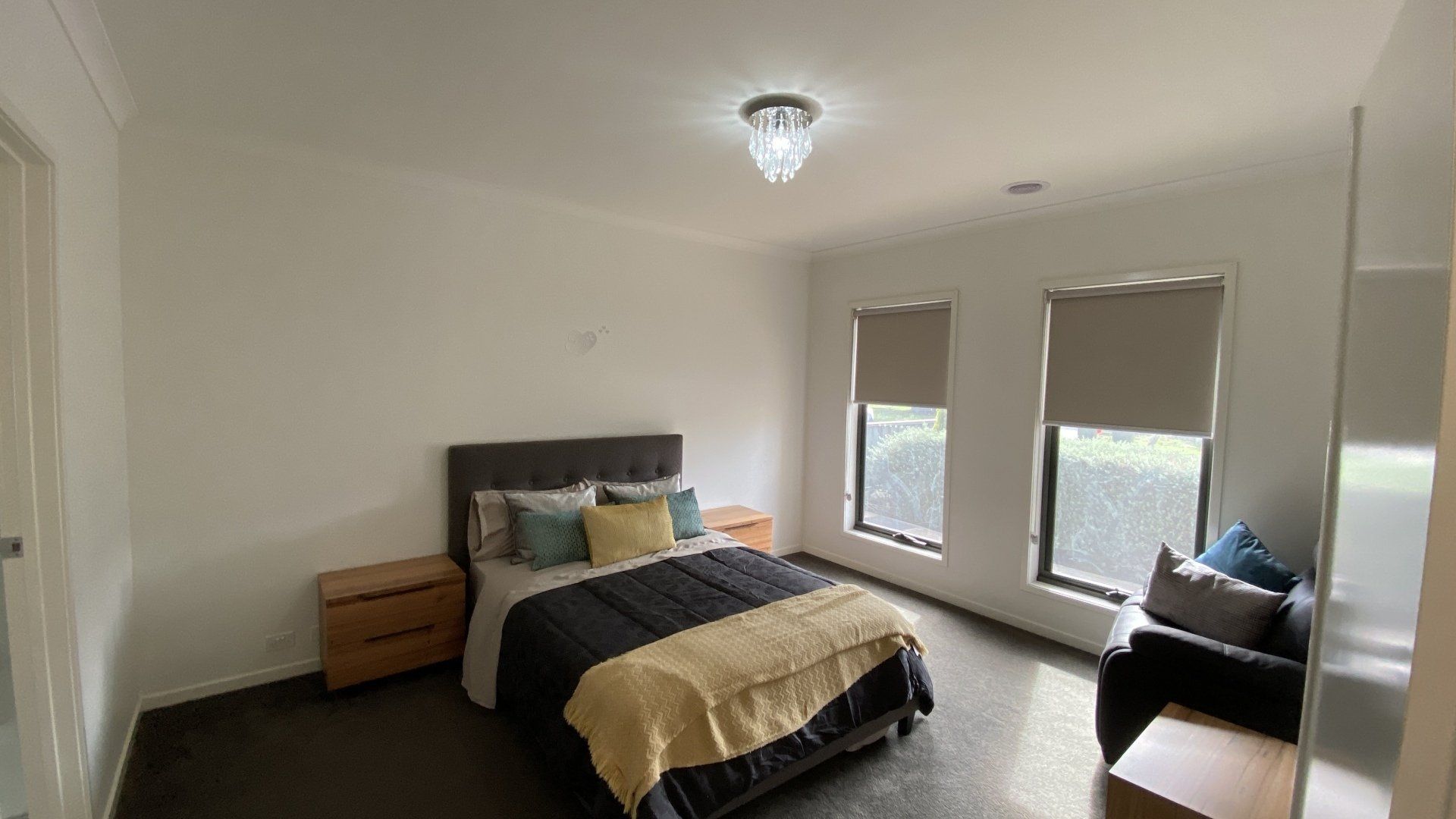 A bedroom with a bed , two nightstands , and two windows.