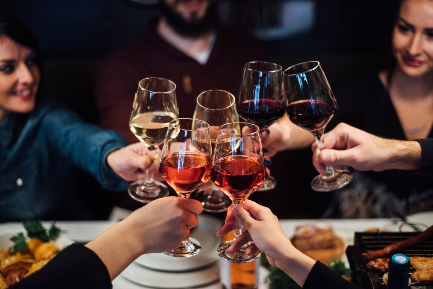 A group of people are toasting with wine glasses at a table.