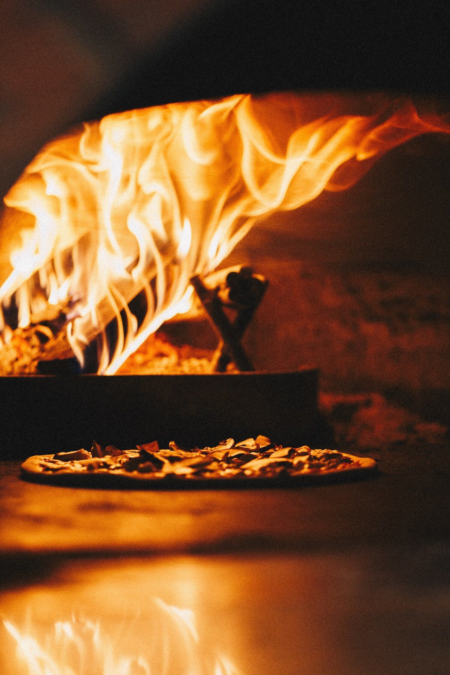 A pizza is being cooked in an oven with flames coming out of it.